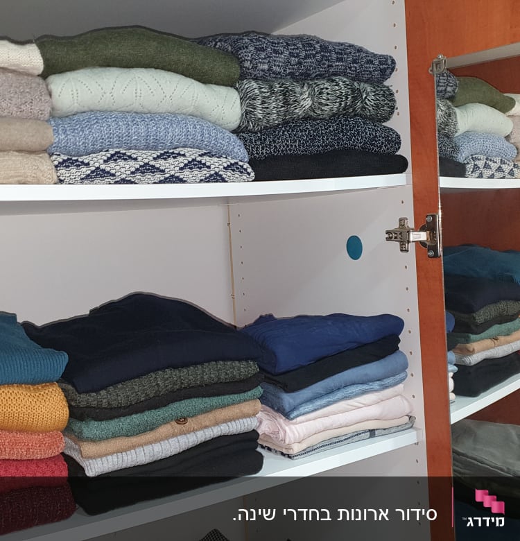 סוודרים מקופלים בארון עץ עם מדפים לבנים